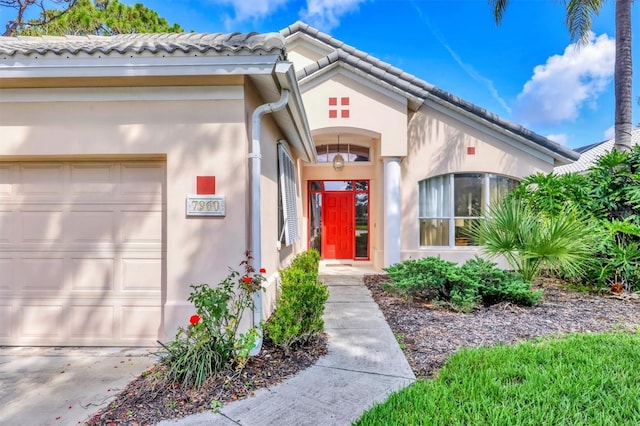 7960 Hampton Ct, University Park, FL 34201 - view of exterior entry with an attached garage and stucco siding