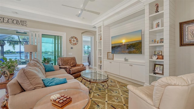 1114 Bearing Ct, Bradenton, FL 34208 - living room with built in shelves, crown molding, a ceiling fan, light wood-style flooring, and arched walkways