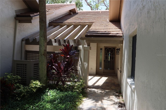 3376 Sandleheath Unit 9, Sarasota, FL 34235 - view of exterior entry with stucco siding and a tiled roof