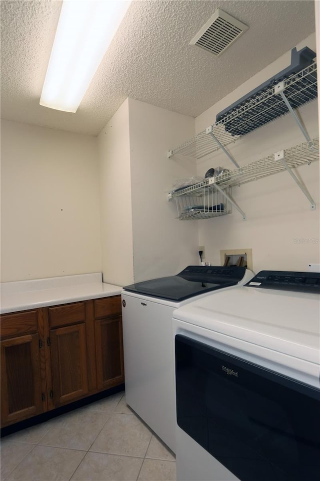 3376 Sandleheath Unit 9, Sarasota, FL 34235 - washroom featuring washing machine and dryer, light tile patterned floors, and a textured ceiling