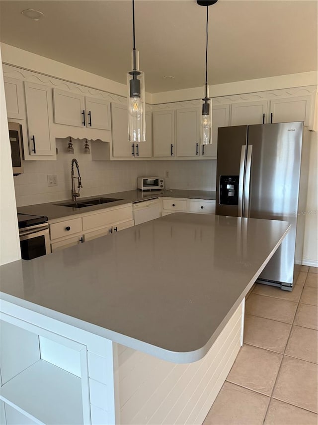 4424 Coco Ridge Cir, Sarasota, FL 34233 - kitchen featuring appliances with stainless steel finishes, light tile patterned flooring, white cabinets, hanging light fixtures, and dark countertops