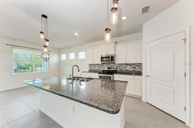 13829 Camden Crest Ter, Bradenton, FL 34211 - kitchen featuring stainless steel appliances, light tile patterned flooring, backsplash, dark stone counters, and a kitchen island with sink