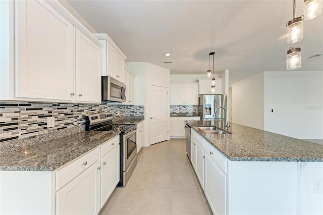 13829 Camden Crest Ter, Bradenton, FL 34211 - kitchen with appliances with stainless steel finishes, tasteful backsplash, white cabinetry, dark stone countertops, and a kitchen island with sink