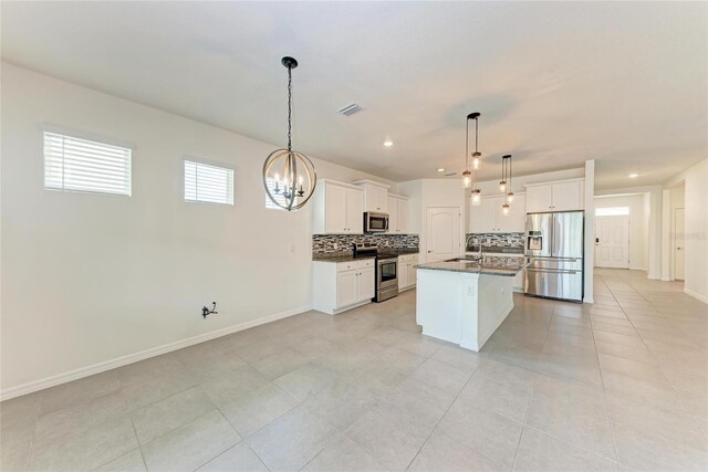 13829 Camden Crest Ter, Bradenton, FL 34211 - kitchen with appliances with stainless steel finishes, backsplash, white cabinetry, a kitchen island with sink, and light tile patterned flooring