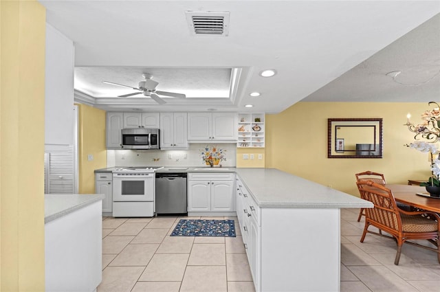 6480 Midnight Pass Rd Unit 503, Sarasota, FL 34242 - kitchen featuring stainless steel appliances, a raised ceiling, a peninsula, light countertops, and light tile patterned floors
