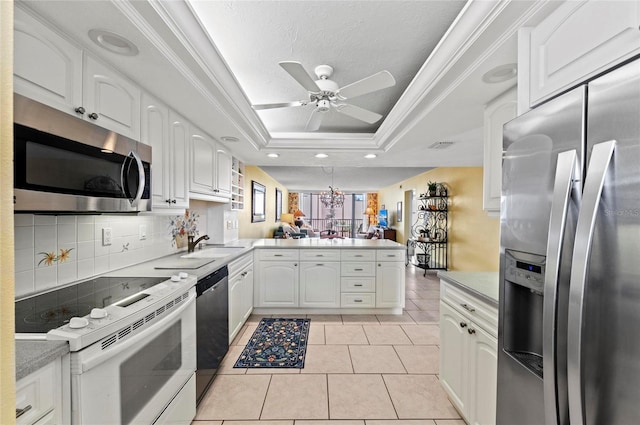 6480 Midnight Pass Rd Unit 503, Sarasota, FL 34242 - kitchen featuring stainless steel appliances, a peninsula, a tray ceiling, ceiling fan, and white cabinetry