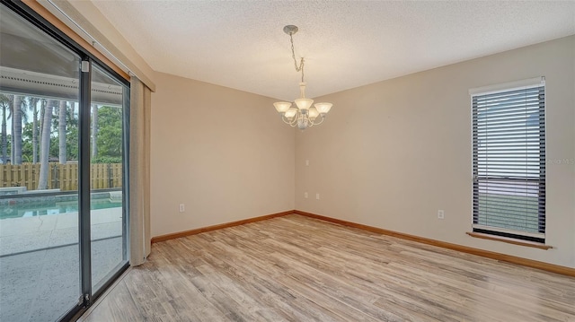 8103 11th Ave NW, Bradenton, FL 34209 - empty room featuring light wood-style floors, plenty of natural light, a chandelier, and a textured ceiling