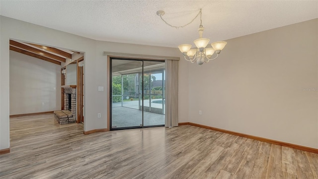 8103 11th Ave NW, Bradenton, FL 34209 - empty room with wood finished floors, a chandelier, a fireplace, and a textured ceiling