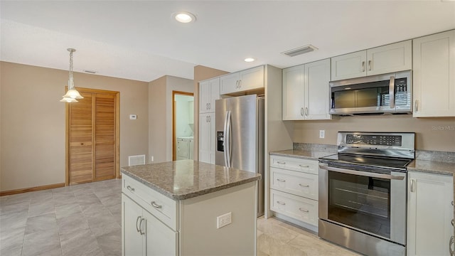 8103 11th Ave NW, Bradenton, FL 34209 - kitchen featuring appliances with stainless steel finishes, a center island, washer / clothes dryer, decorative light fixtures, and light stone countertops