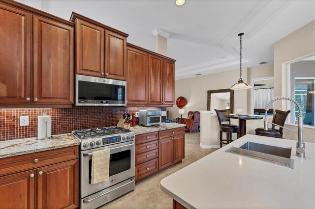 6305 Golden Eye Gln, Lakewood Ranch, FL 34202 - kitchen with appliances with stainless steel finishes, backsplash, hanging light fixtures, and brown cabinets