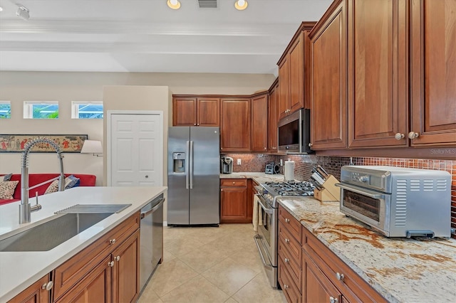 6305 Golden Eye Gln, Lakewood Ranch, FL 34202 - kitchen featuring appliances with stainless steel finishes, tasteful backsplash, brown cabinets, light tile patterned flooring, and recessed lighting