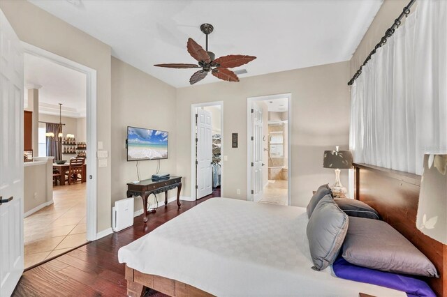 6305 Golden Eye Gln, Lakewood Ranch, FL 34202 - bedroom featuring a chandelier, wood finished floors, a spacious closet, a ceiling fan, and ensuite bathroom