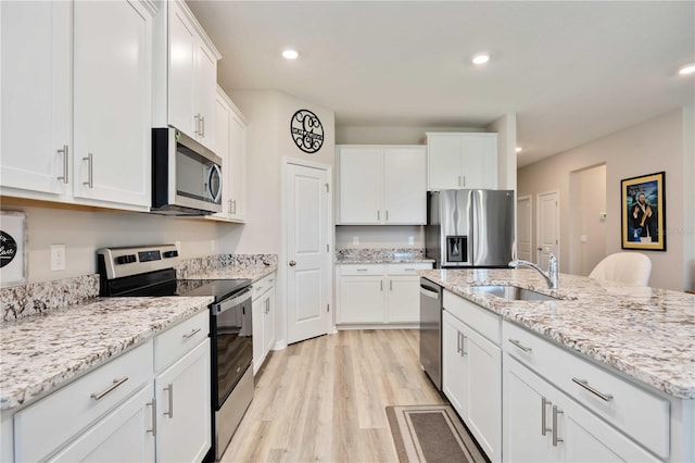 12357 Nantahala Run, Parrish, FL 34219 - kitchen featuring appliances with stainless steel finishes, light wood-type flooring, white cabinets, an island with sink, and recessed lighting