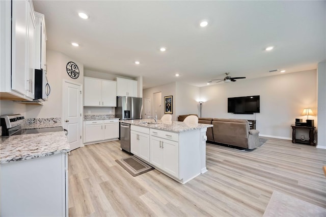 12357 Nantahala Run, Parrish, FL 34219 - kitchen with light wood-style flooring, a ceiling fan, open floor plan, stainless steel appliances, and a kitchen island with sink