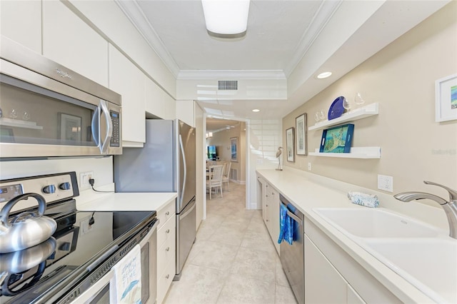 4805 Gulf Of Mexico Dr Unit 105, Longboat Key, FL 34228 - kitchen with appliances with stainless steel finishes, ornamental molding, white cabinets, light countertops, and light tile patterned floors