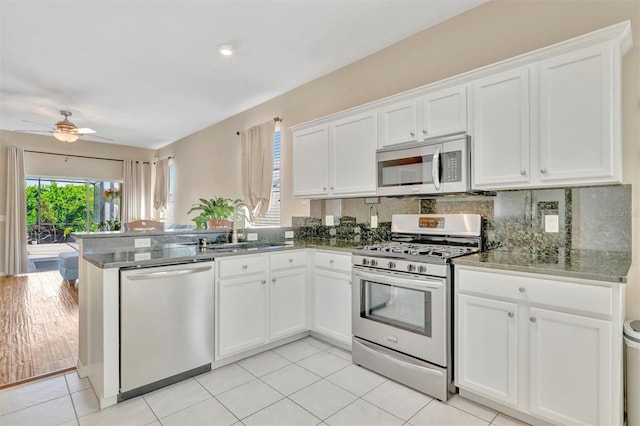 14255 Gnatcatcher Ter, Lakewood Ranch, FL 34202 - kitchen with appliances with stainless steel finishes, white cabinetry, a peninsula, a ceiling fan, and decorative backsplash