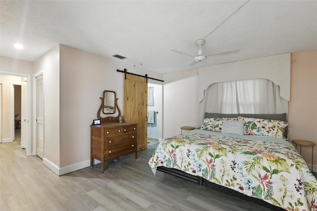 326 Mann Ave SE, Port Charlotte, FL 33952 - bedroom featuring wood finished floors, a barn door, a textured ceiling, ceiling fan, and a closet