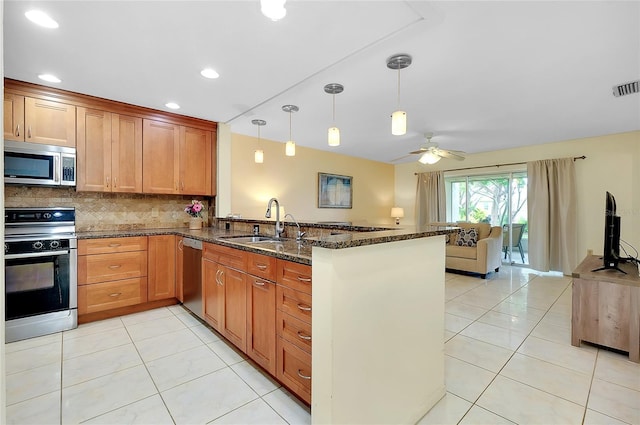4339 Bowling Green Cir Unit 19, Sarasota, FL 34233 - kitchen featuring appliances with stainless steel finishes, a peninsula, backsplash, dark stone counters, and light tile patterned floors
