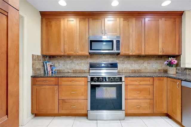 4339 Bowling Green Cir Unit 19, Sarasota, FL 34233 - kitchen with appliances with stainless steel finishes, dark stone counters, tasteful backsplash, recessed lighting, and brown cabinetry