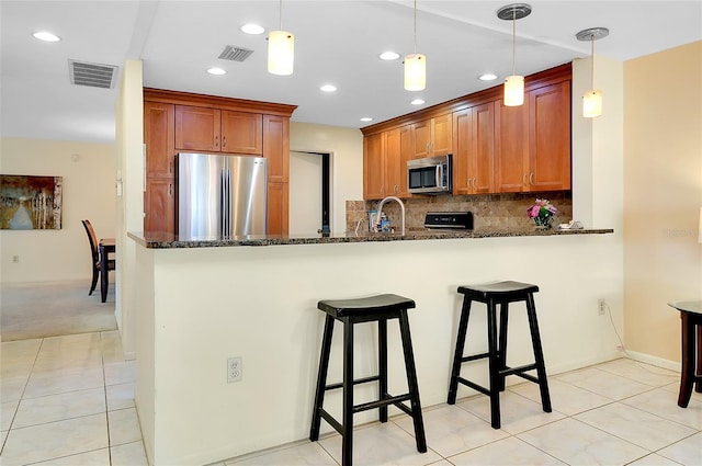 4339 Bowling Green Cir Unit 19, Sarasota, FL 34233 - kitchen with stainless steel appliances, dark stone counters, a breakfast bar area, a peninsula, and recessed lighting