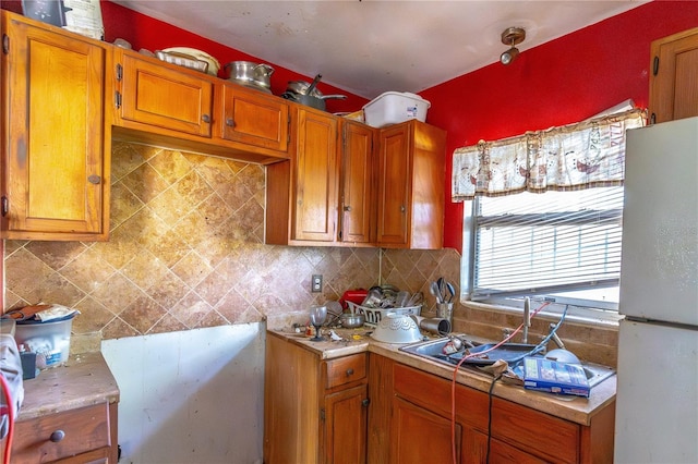 kitchen with freestanding refrigerator, brown cabinetry, and light countertops