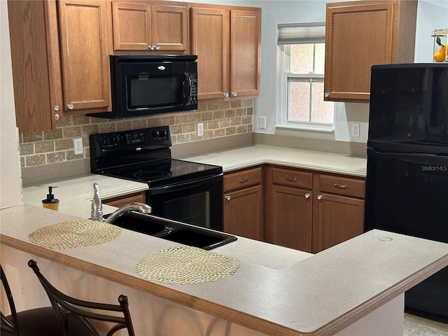 8809 White Sage Loop, Lakewood Ranch, FL 34202 - kitchen with black appliances, brown cabinets, light countertops, decorative backsplash, and a kitchen bar