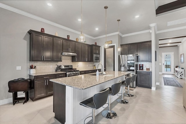 10347 Coastal Shores Dr, Parrish, FL 34219 - kitchen with appliances with stainless steel finishes, under cabinet range hood, dark brown cabinets, backsplash, and light tile patterned floors