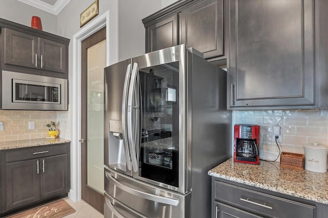 10347 Coastal Shores Dr, Parrish, FL 34219 - kitchen with stainless steel appliances, backsplash, light stone counters, ornamental molding, and dark brown cabinets