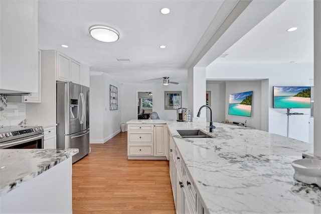 6962 Belgrave Dr, Sarasota, FL 34242 - kitchen featuring appliances with stainless steel finishes, light wood-style flooring, white cabinetry, light stone countertops, and ceiling fan