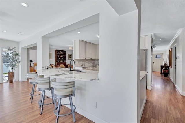6962 Belgrave Dr, Sarasota, FL 34242 - kitchen with a kitchen breakfast bar, light wood-style floors, decorative backsplash, and recessed lighting