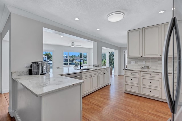 6962 Belgrave Dr, Sarasota, FL 34242 - kitchen featuring stainless steel fridge, light wood-type flooring, a peninsula, light stone countertops, and backsplash