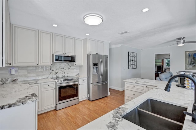 6962 Belgrave Dr, Sarasota, FL 34242 - kitchen featuring stainless steel appliances, backsplash, light stone countertops, light wood-style floors, and recessed lighting