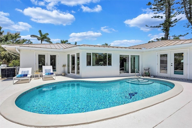 6962 Belgrave Dr, Sarasota, FL 34242 - rear view of house with french doors, a standing seam roof, a metal roof, an outdoor pool, and a patio