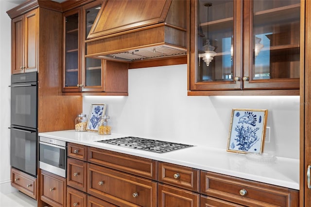 2251 Gulf Of Mexico Dr Unit 301, Longboat Key, FL 34228 - kitchen featuring custom exhaust hood, stainless steel gas stovetop, brown cabinetry, light countertops, and glass insert cabinets
