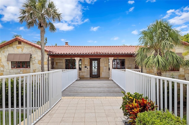 2251 Gulf Of Mexico Dr Unit 301, Longboat Key, FL 34228 - mediterranean / spanish house featuring a tiled roof, stone siding, a porch, and a chimney