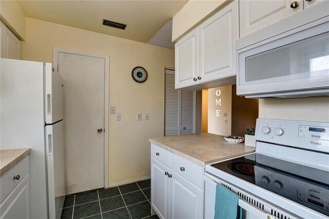 2716 Hidden Lake Blvd Unit C, Sarasota, FL 34237 - kitchen featuring white appliances, white cabinets, light countertops, and dark tile patterned floors