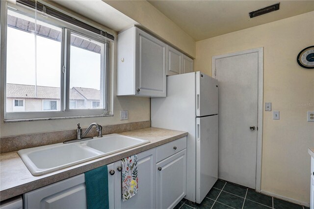2716 Hidden Lake Blvd Unit C, Sarasota, FL 34237 - kitchen featuring freestanding refrigerator, dark tile patterned floors, and white cabinets