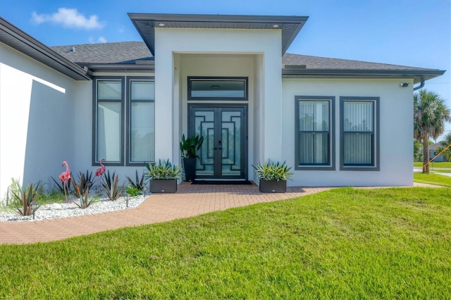 10270 Castanet Ave, Englewood, FL 34224 - view of exterior entry featuring stucco siding, roof with shingles, and a yard