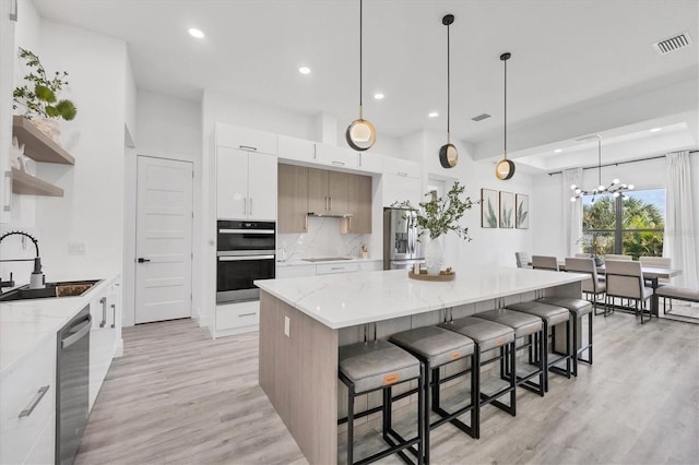 10270 Castanet Ave, Englewood, FL 34224 - kitchen featuring stainless steel appliances, modern cabinets, white cabinets, light wood-style flooring, and decorative backsplash