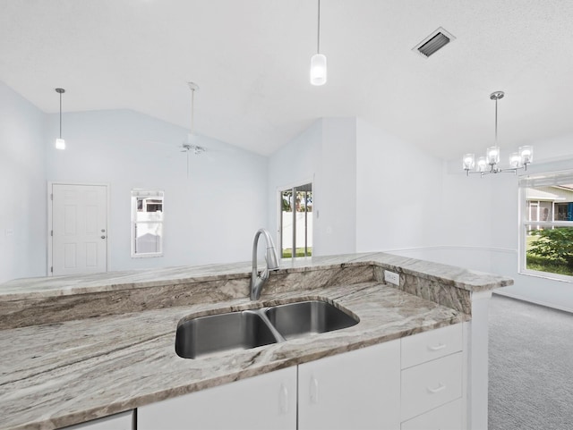 3223 Jamaica St, Sarasota, FL 34231 - kitchen with carpet floors, lofted ceiling, white cabinetry, light stone counters, and decorative light fixtures