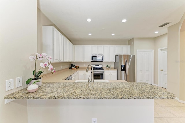 7039 Woodmore Ter, Lakewood Ranch, FL 34202 - kitchen with appliances with stainless steel finishes, light tile patterned floors, a peninsula, light stone counters, and recessed lighting