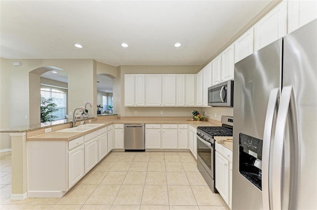 7039 Woodmore Ter, Lakewood Ranch, FL 34202 - kitchen featuring stainless steel appliances, arched walkways, light tile patterned floors, light countertops, and white cabinetry