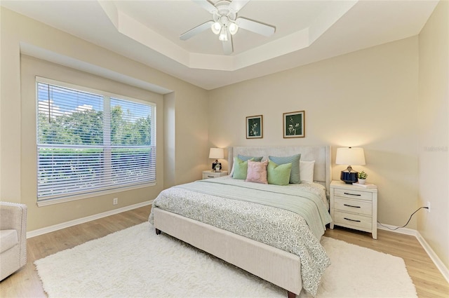 7039 Woodmore Ter, Lakewood Ranch, FL 34202 - bedroom with light wood-type flooring, a raised ceiling, and a ceiling fan