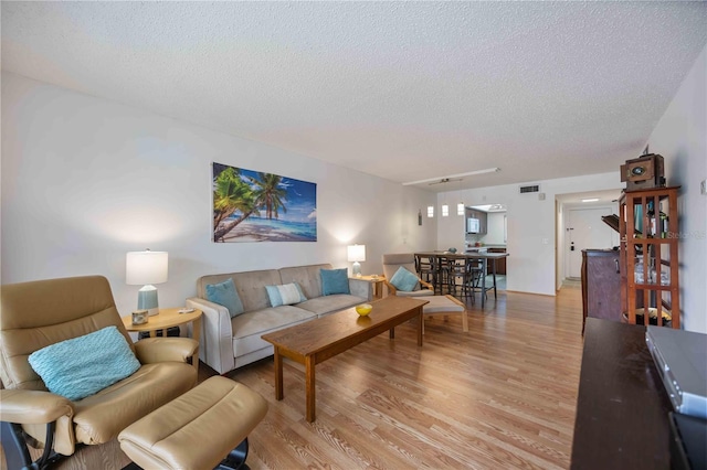 2220 Stickney Point Rd Unit 528, Sarasota, FL 34231 - living room with a textured ceiling and light wood-style floors