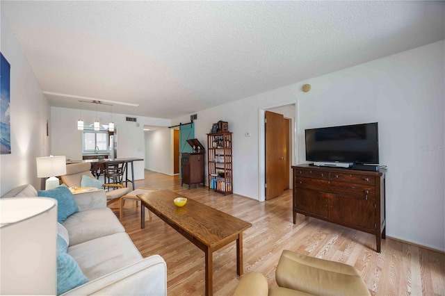 2220 Stickney Point Rd Unit 528, Sarasota, FL 34231 - living area with a barn door, a textured ceiling, and light wood-type flooring