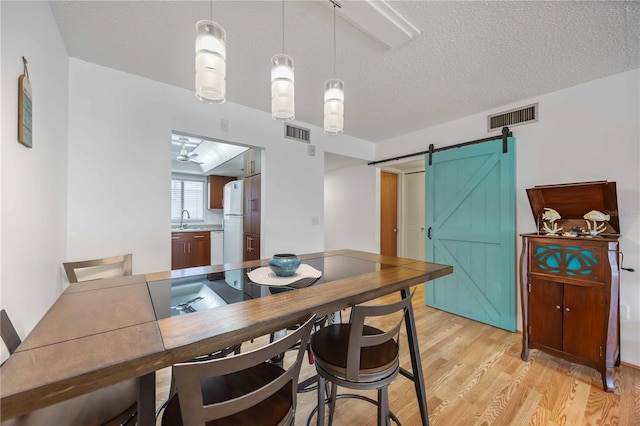 2220 Stickney Point Rd Unit 528, Sarasota, FL 34231 - dining space with a barn door, light wood-style flooring, and a textured ceiling