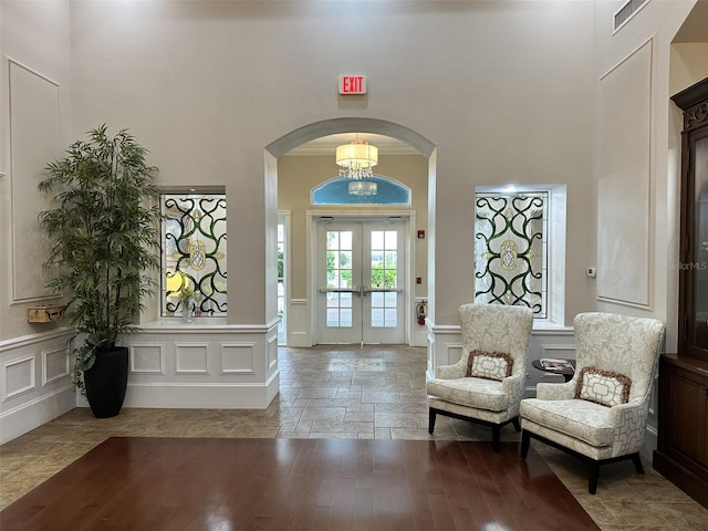 6713 Stone River Rd Unit 101, Bradenton, FL 34203 - foyer entrance featuring a decorative wall, arched walkways, french doors, a towering ceiling, and a wainscoted wall
