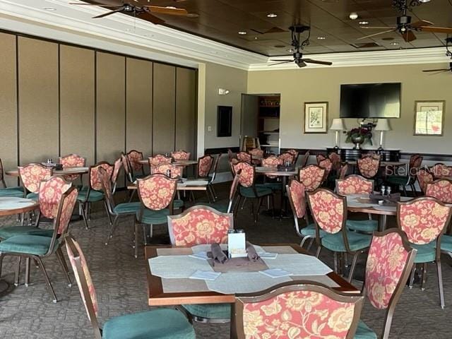 6713 Stone River Rd Unit 101, Bradenton, FL 34203 - dining room featuring a ceiling fan, ornamental molding, a tray ceiling, and carpet