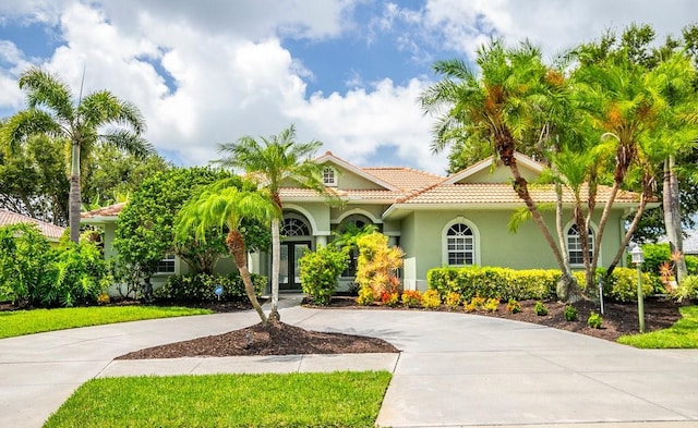 471 Park Trace Blvd, Osprey, FL 34229 - mediterranean / spanish-style home with curved driveway, a tiled roof, stucco siding, and french doors