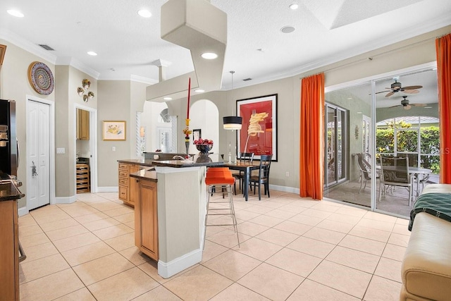 471 Park Trace Blvd, Osprey, FL 34229 - kitchen featuring a kitchen bar, crown molding, dark countertops, light tile patterned floors, and ceiling fan